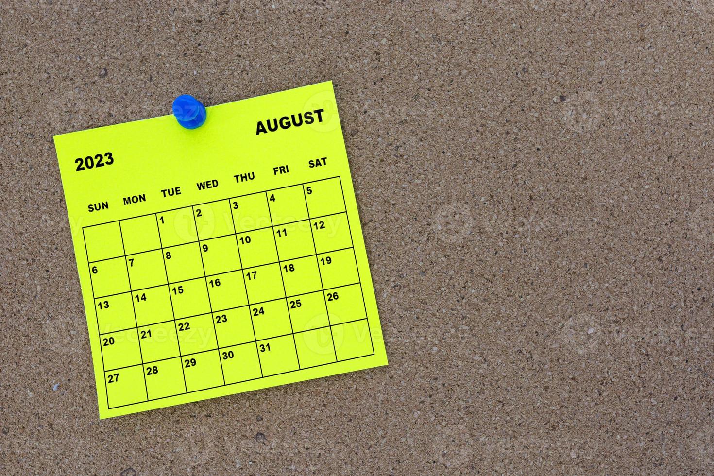 agosto de 2023 calendario de notas adhesivas amarillas con pin en cartelera de corcho. foto