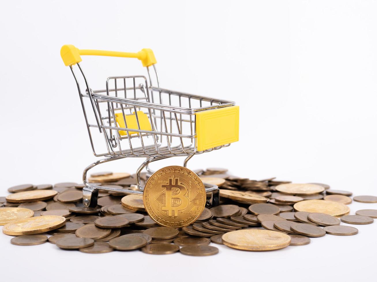 Pay crypto currency the supermarket cart is filled with gold coins of bitcoin on a white background. Copy space photo