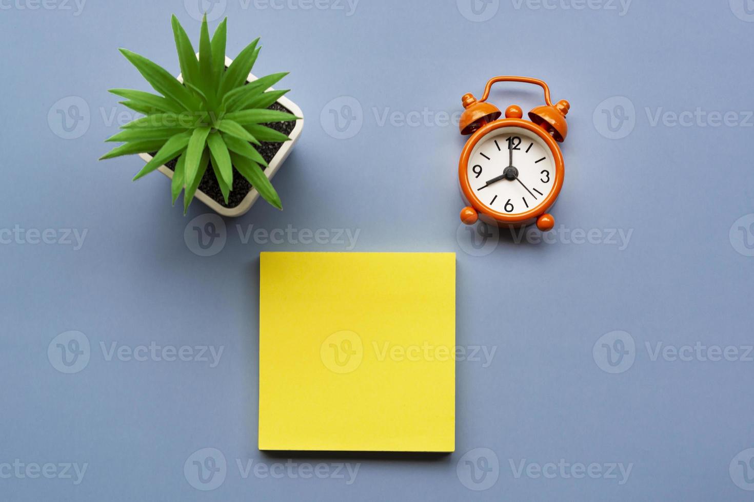 Adhesive Note with potted plant and alarm clock set at 8 o'clock. Copy space. photo