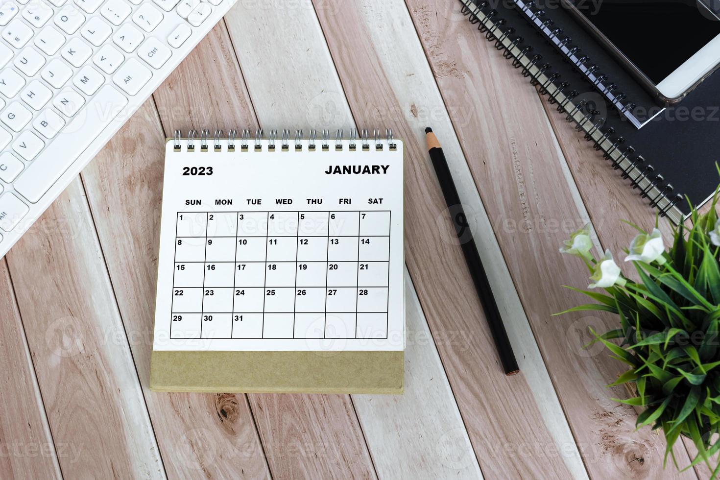 White January 2023 calendar against wooden desk photo