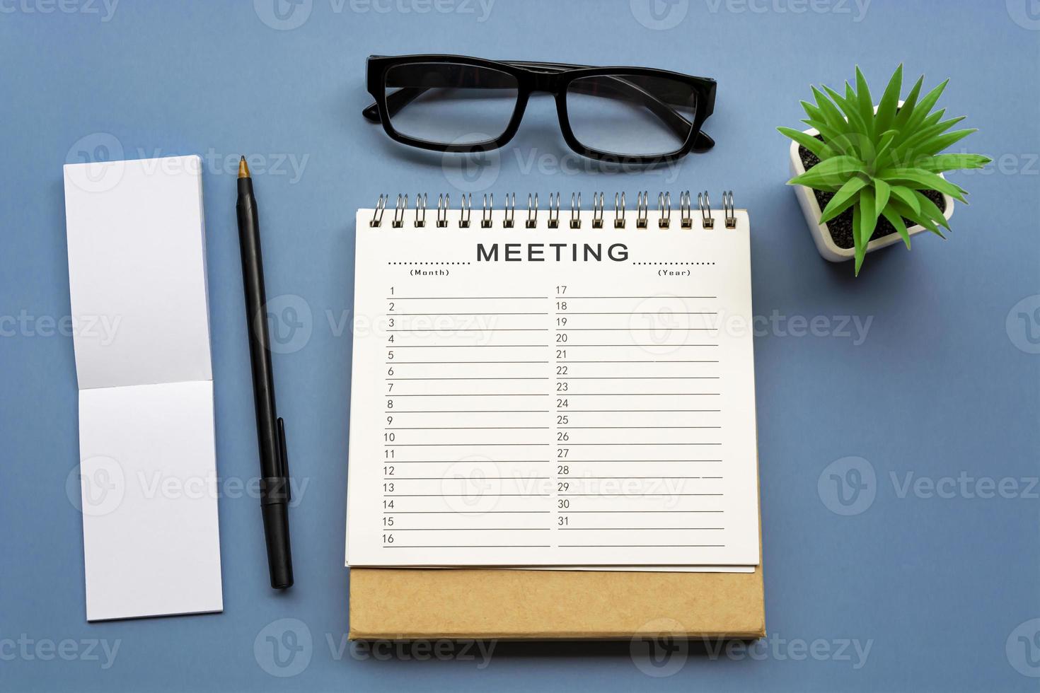 Meeting timetable calendar with notepad on blue background. Business concept. photo