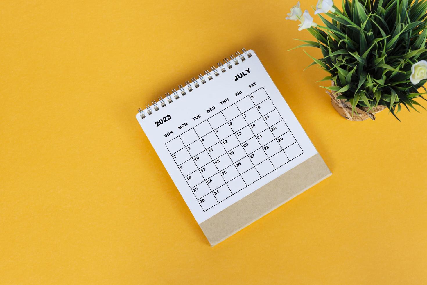 July 2023 desk calendar on yellow background. Directly above. Flat lay. photo