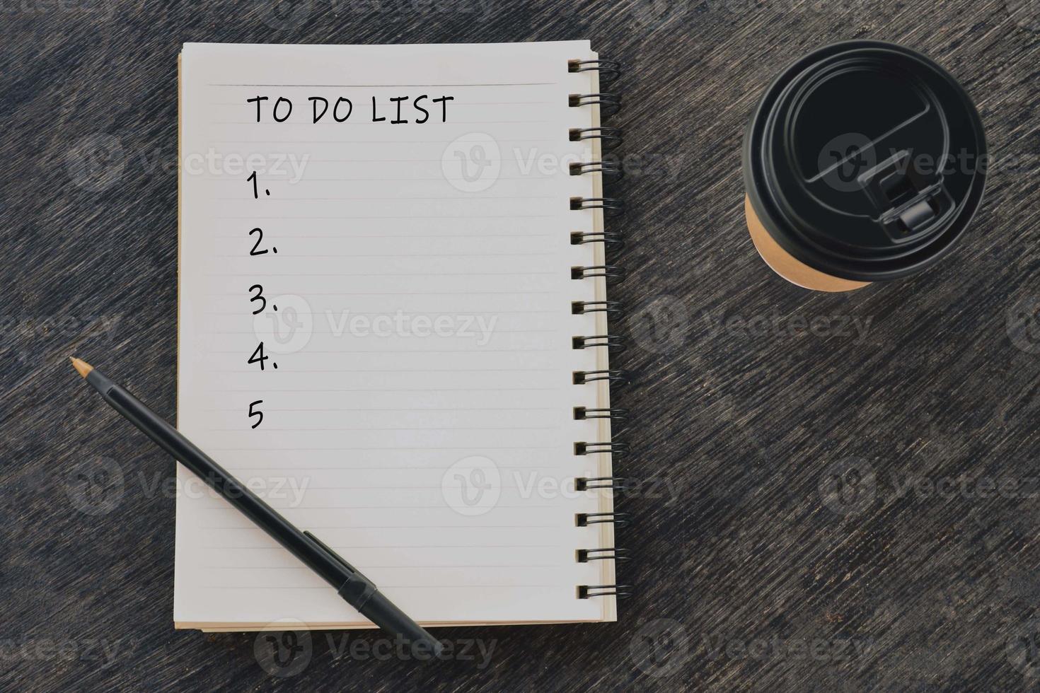 hacer una lista de palabras escritas en el bloc de notas con una taza de café desechable y un bolígrafo. foto