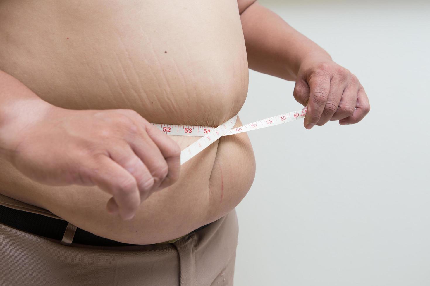 hombre gordo sosteniendo una cinta métrica foto