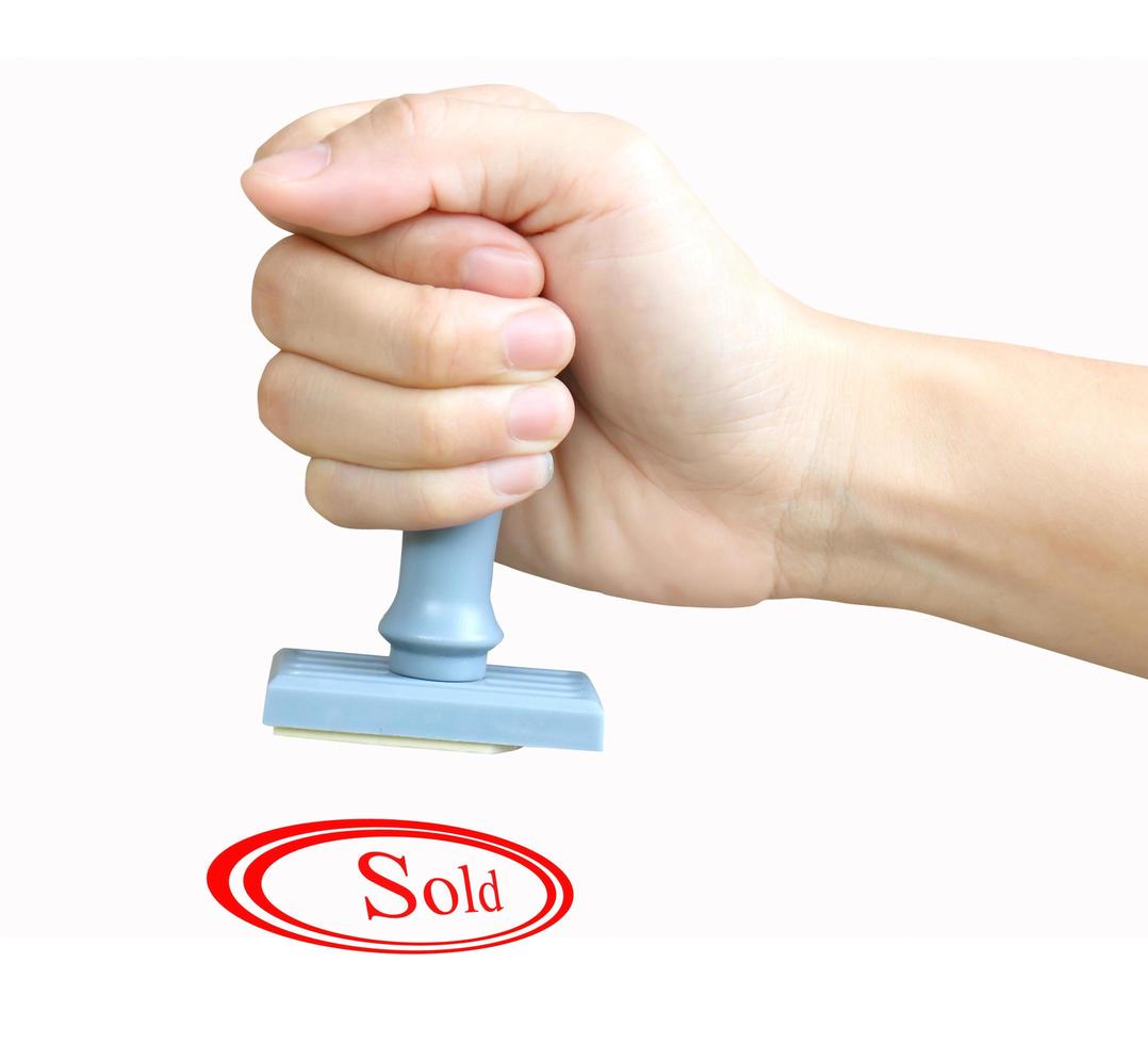 Hand holding a rubber stamp with the word Sold photo