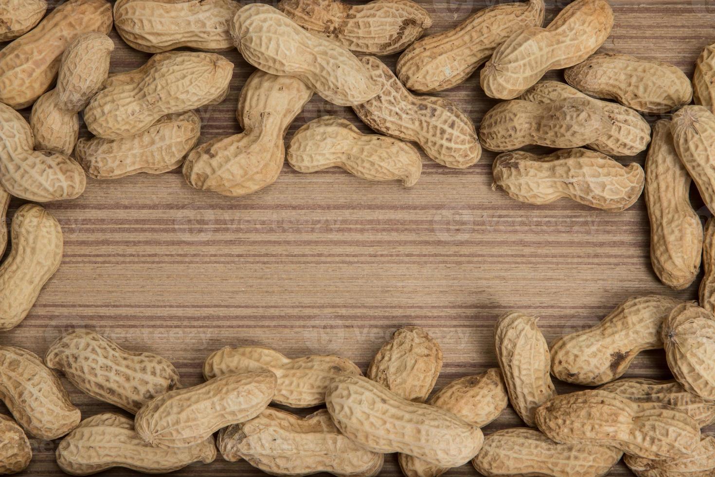 peanuts in shells over wood background photo