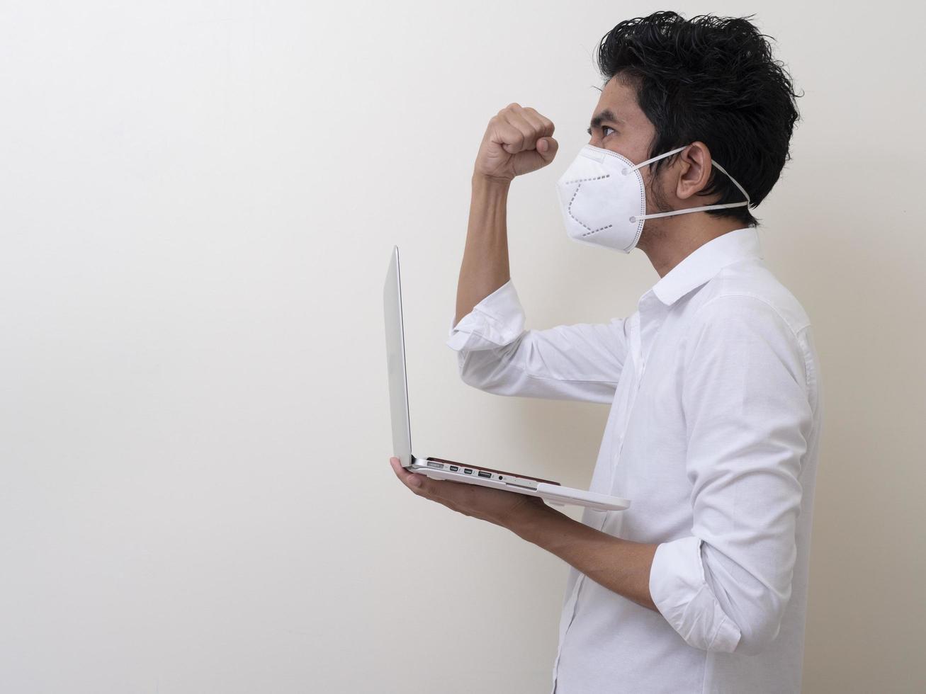 Business man in medical face mask works on laptop at home photo