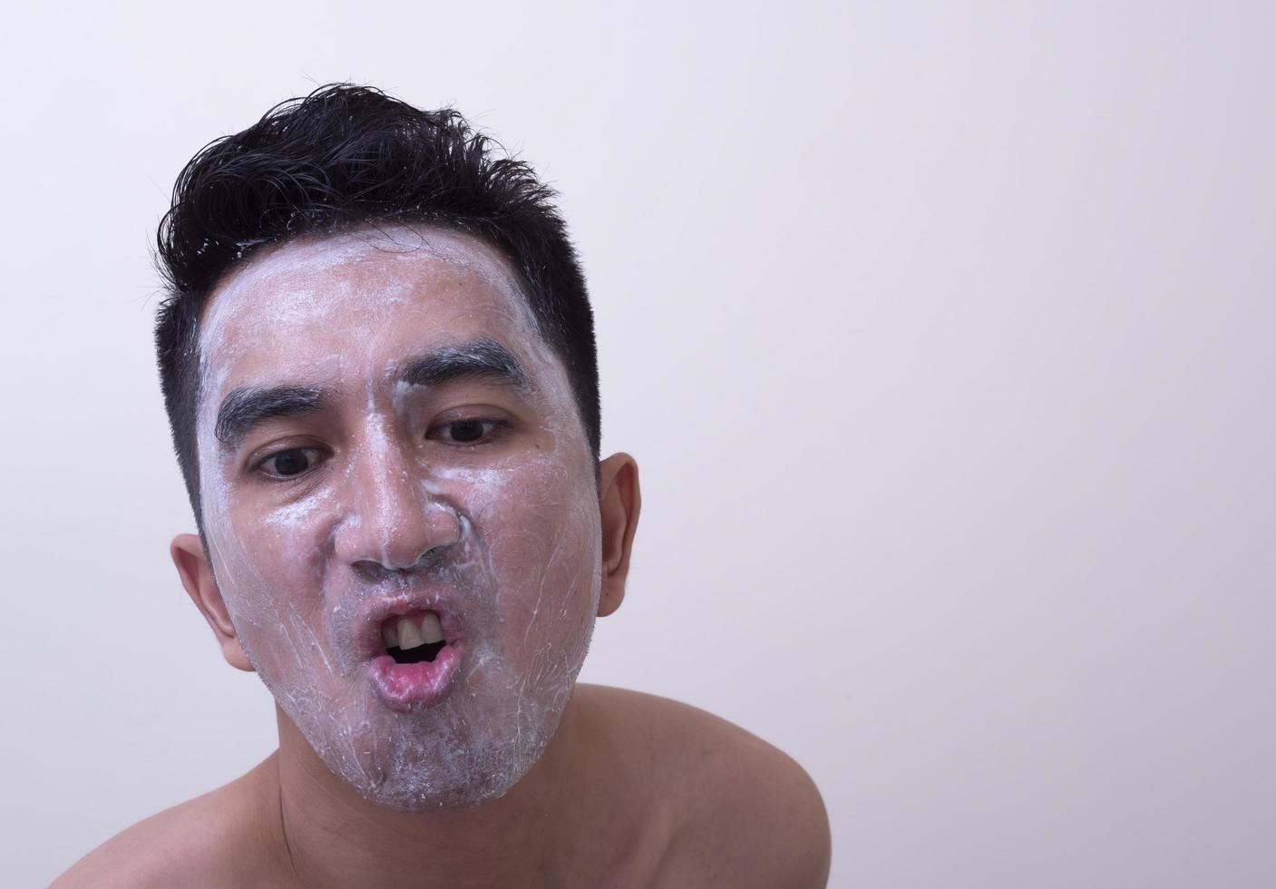 Asian handsome young man applying cream at his face with smiley face, Skin care concept photo