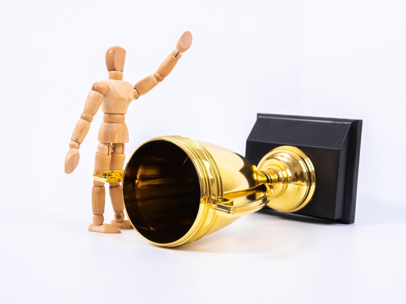 Wooden toy figure and golden trophy cup on white background photo