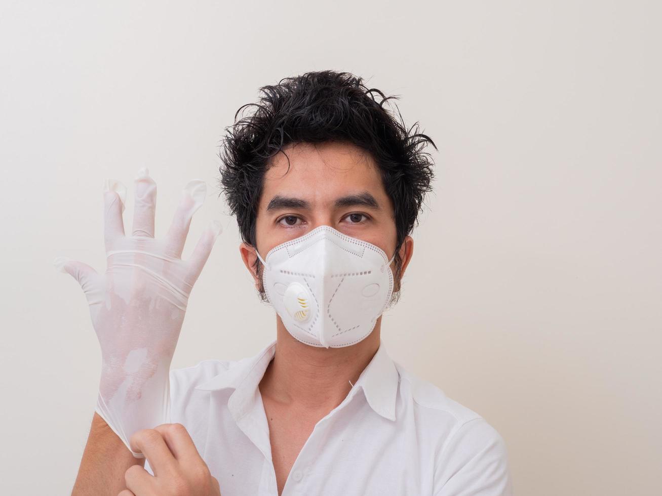 Confident man surgeon in medical mask on face wearing protective sterile glove on hand photo