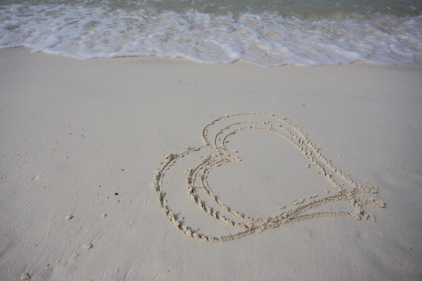 hearts drawn on the sand of a beach photo