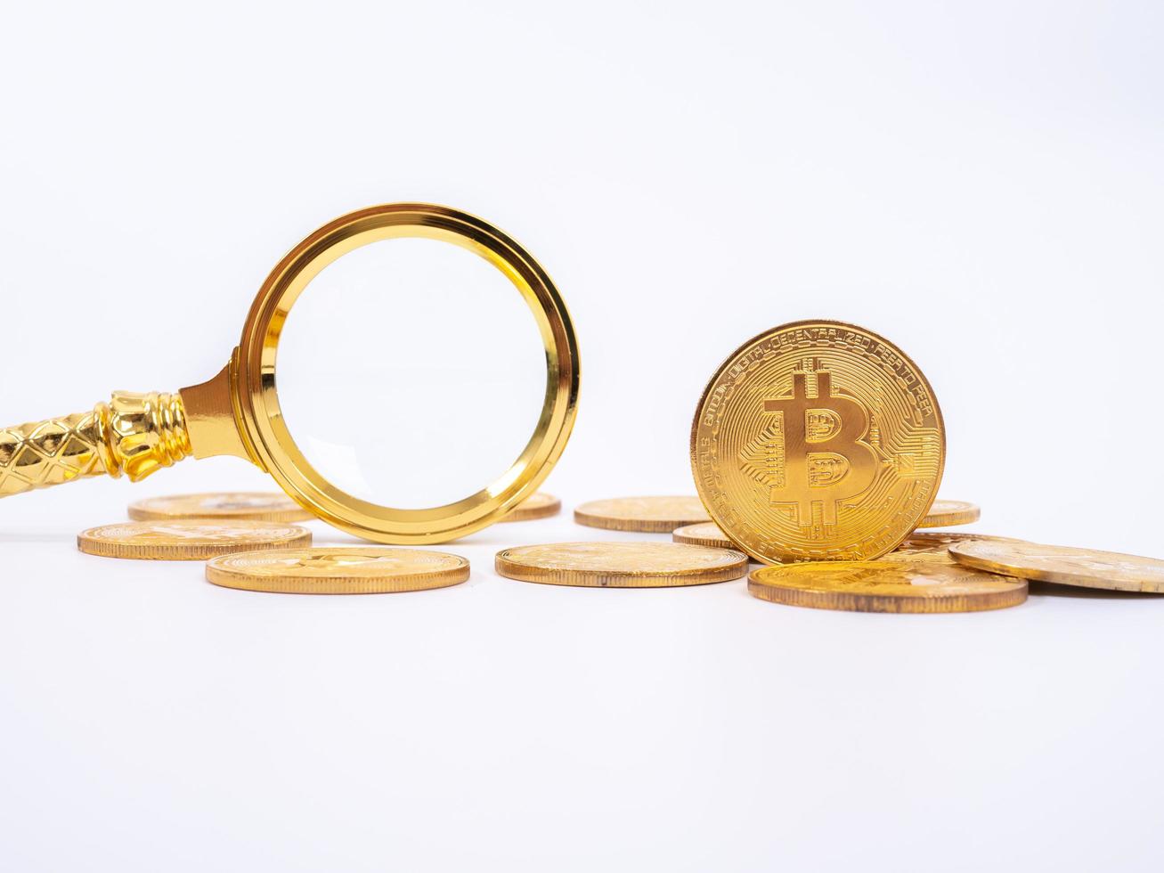 Golden Bitcoin replica and magnifying glass on white   background.Business and finance concept. photo