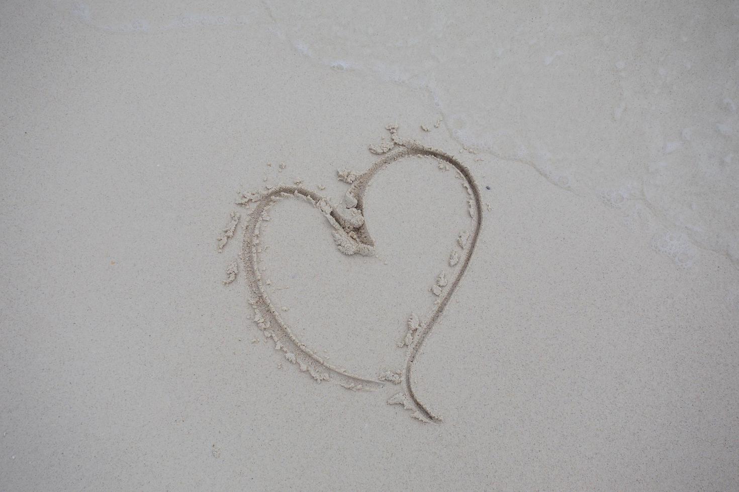 corazones dibujados en la arena de una playa foto