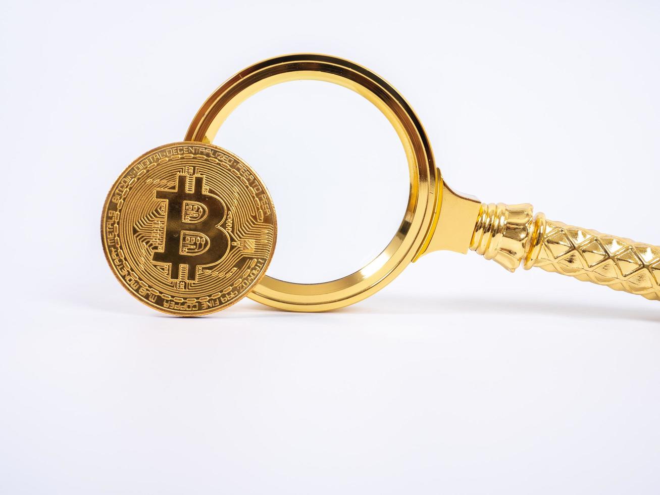 Golden Bitcoin replica and magnifying glass on white   background.Business and finance concept. photo