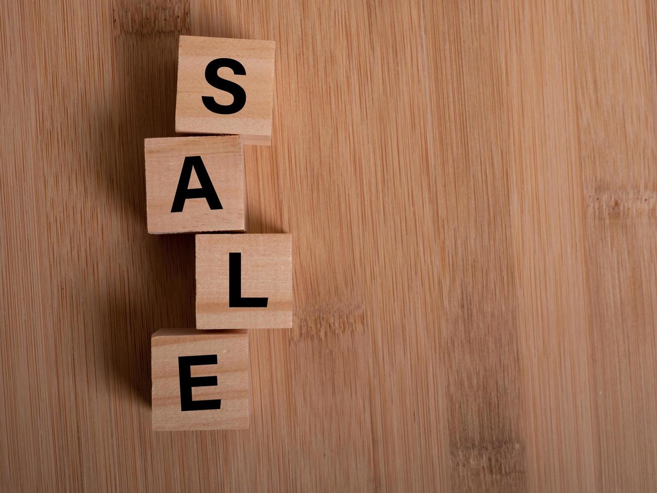 Wooden cubes with word SALE on blue table photo