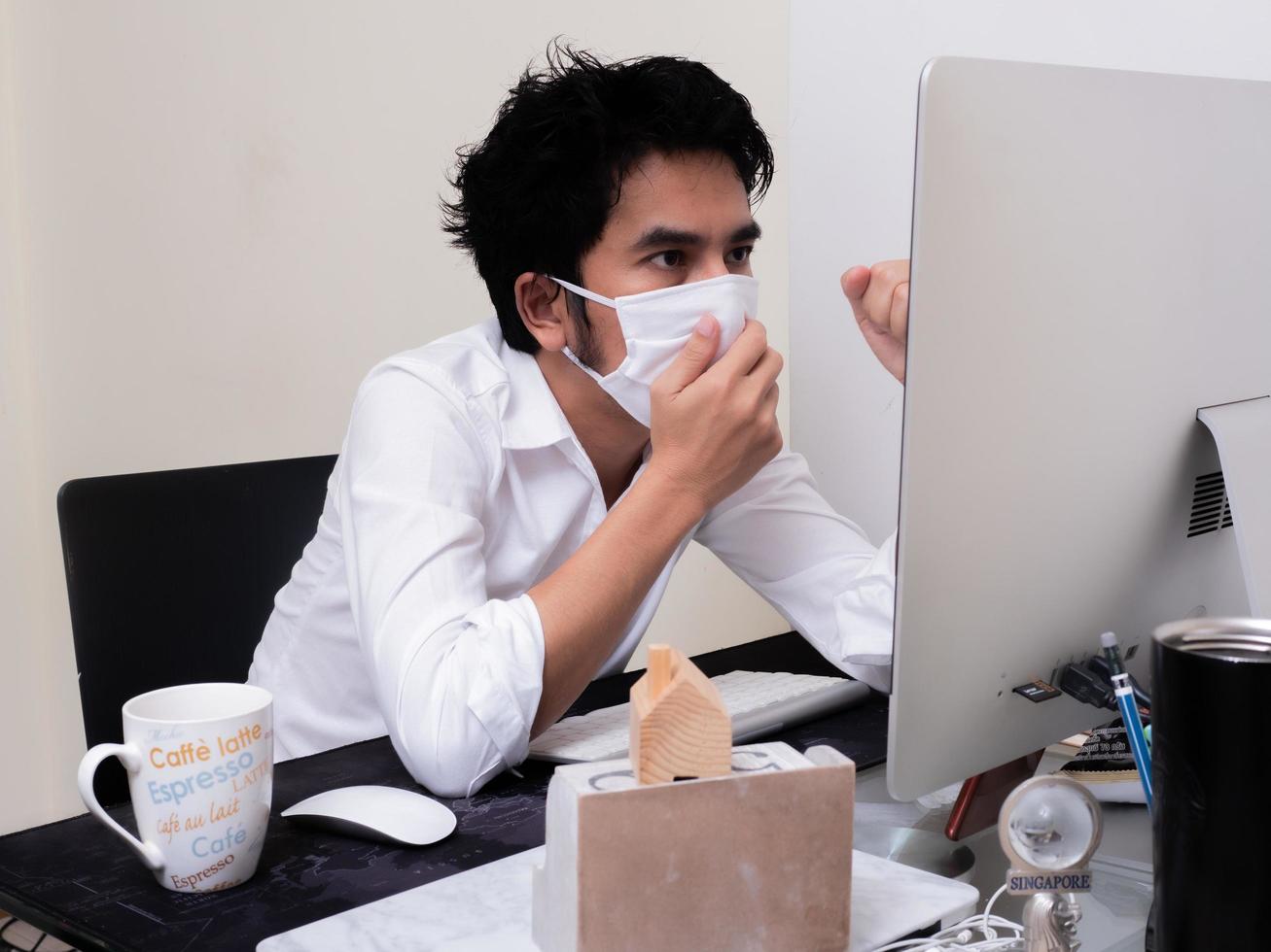 Young Asian boy wearing face mask working on laptop computer during coronavirus pandemic photo