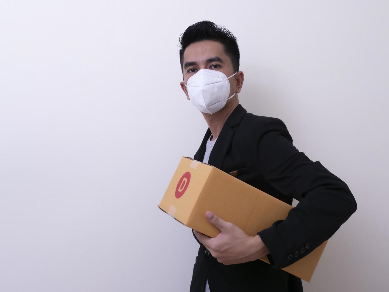 Happy delivery service employee in medical face mask carry cardboard box in hand photo