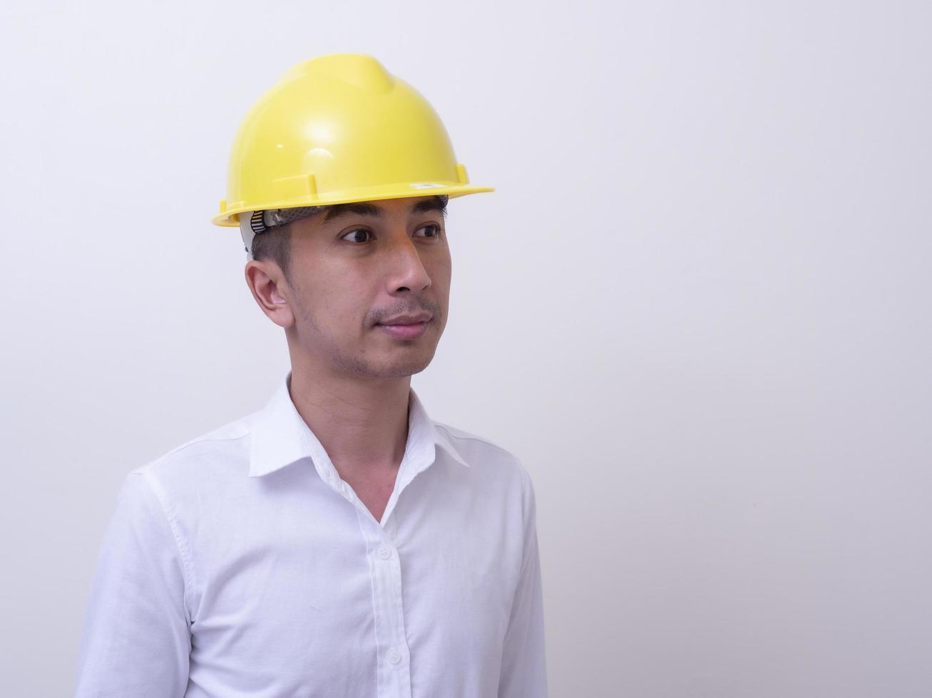 engineer with hands crossed wearing yellow helmet on white background photo