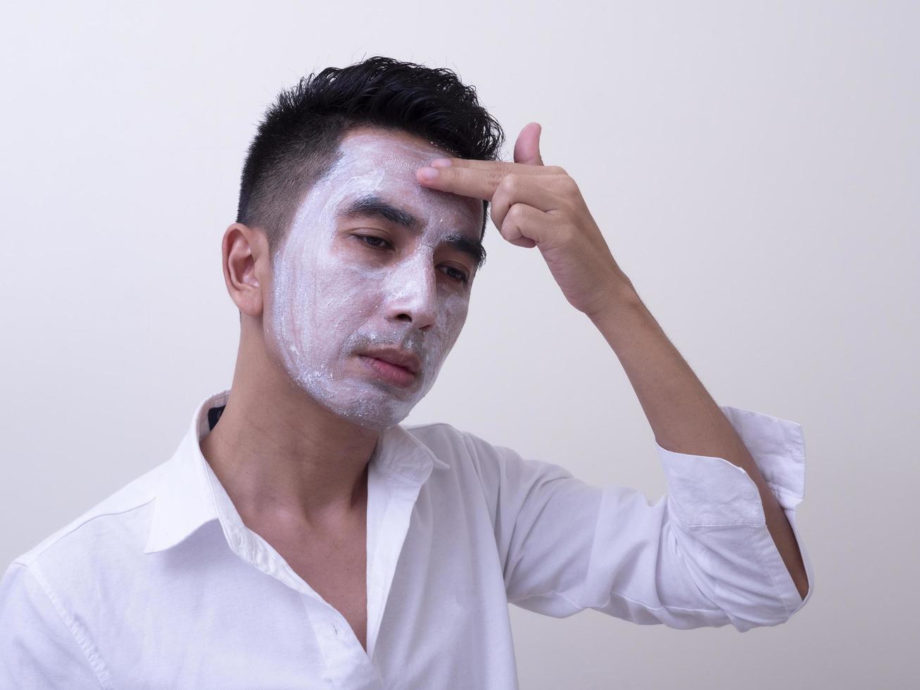 Asian handsome young man applying cream at his face with smiley face, Skin care concept photo