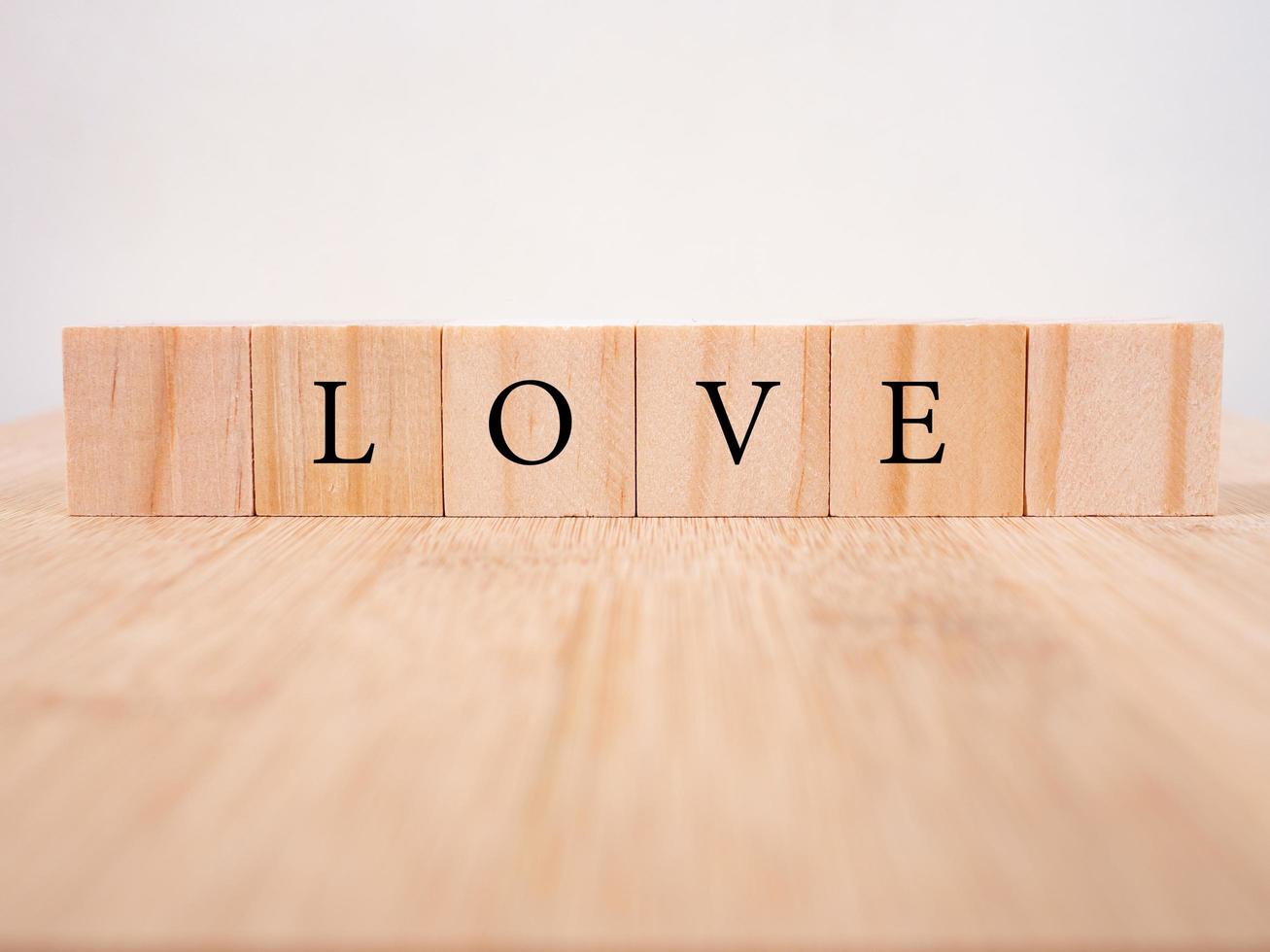 palabra amor en cubos de madera con corazón rojo, primer plano cerca del concepto de San Valentín de fondo blanco foto