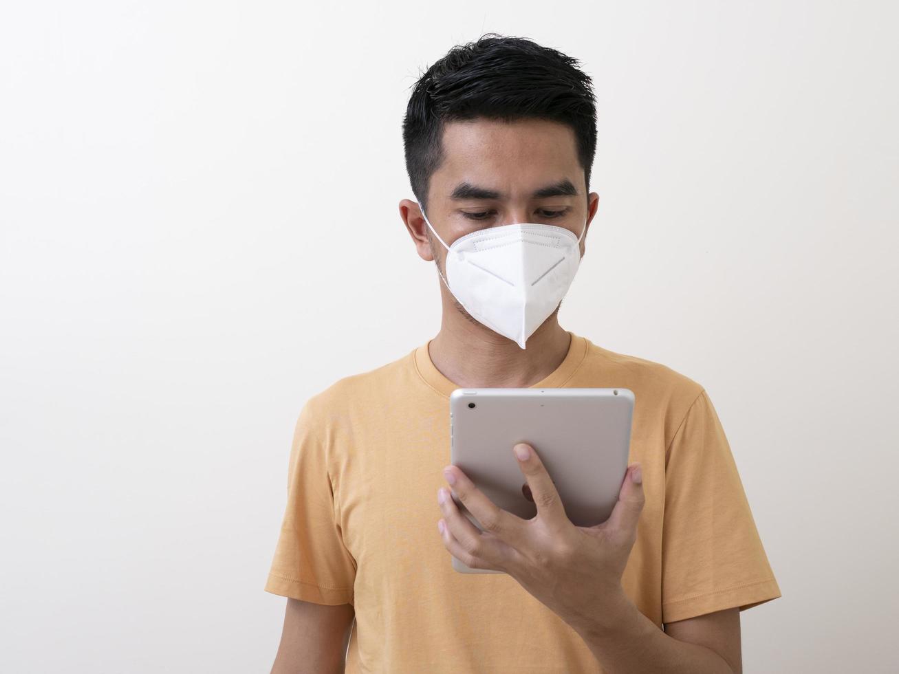 Man with digital tablet  wears surgical mask to protect from virus photo