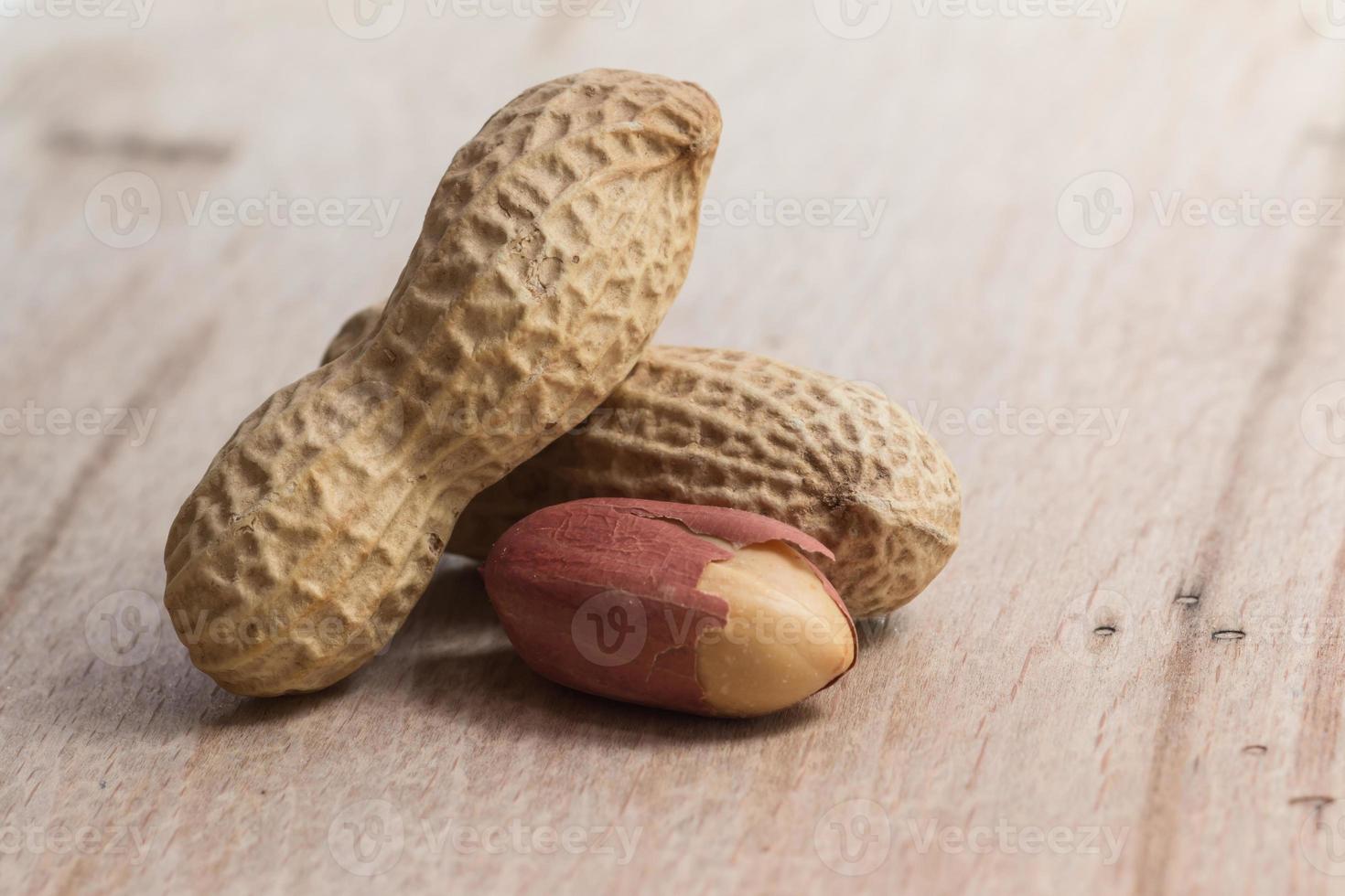 peanuts in shells over wood background photo