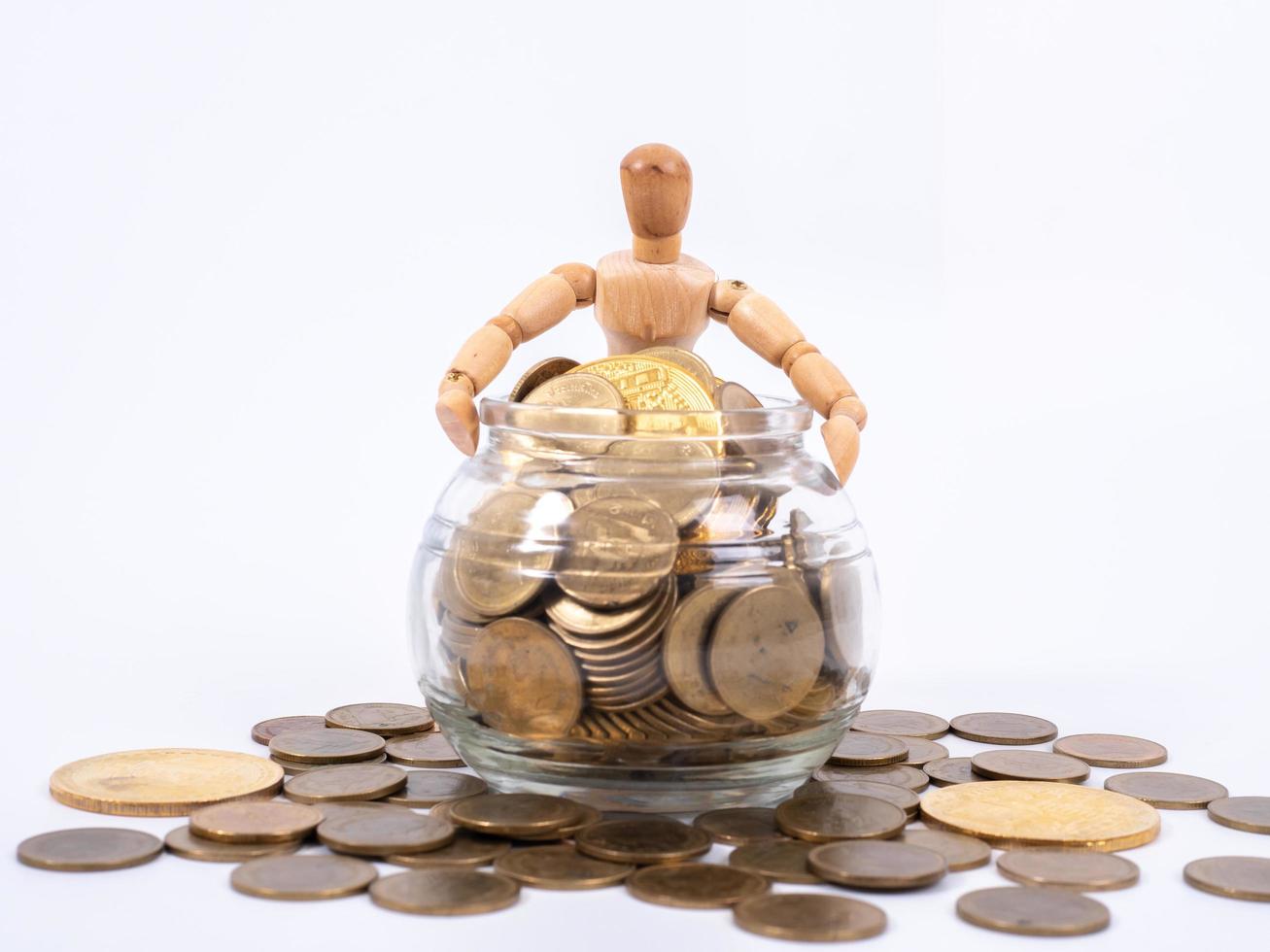 Miniature wooden figure sits on spilled jar with coins. Business concept with coins. photo