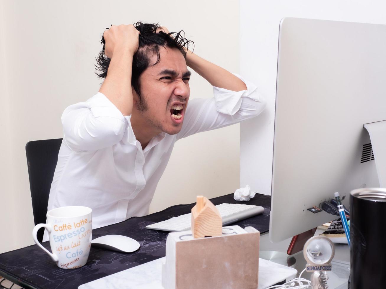 Serious Asian man is working with laptop in his apartment bedroom in concept of Work From Home and Work at Home photo
