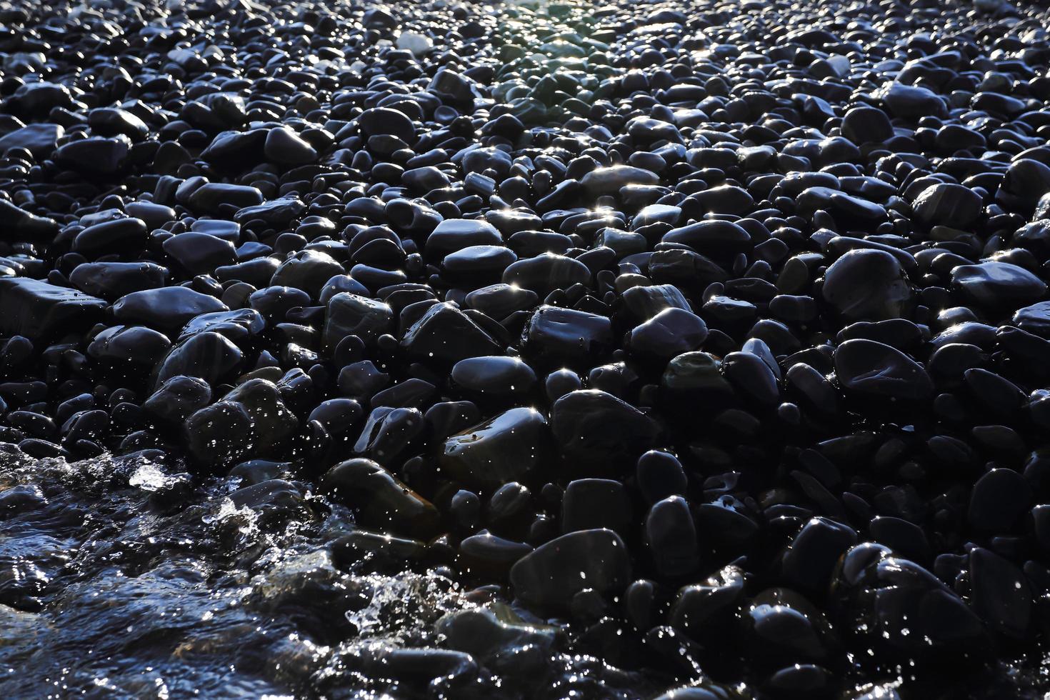 Colorful pebbles touching wave photo