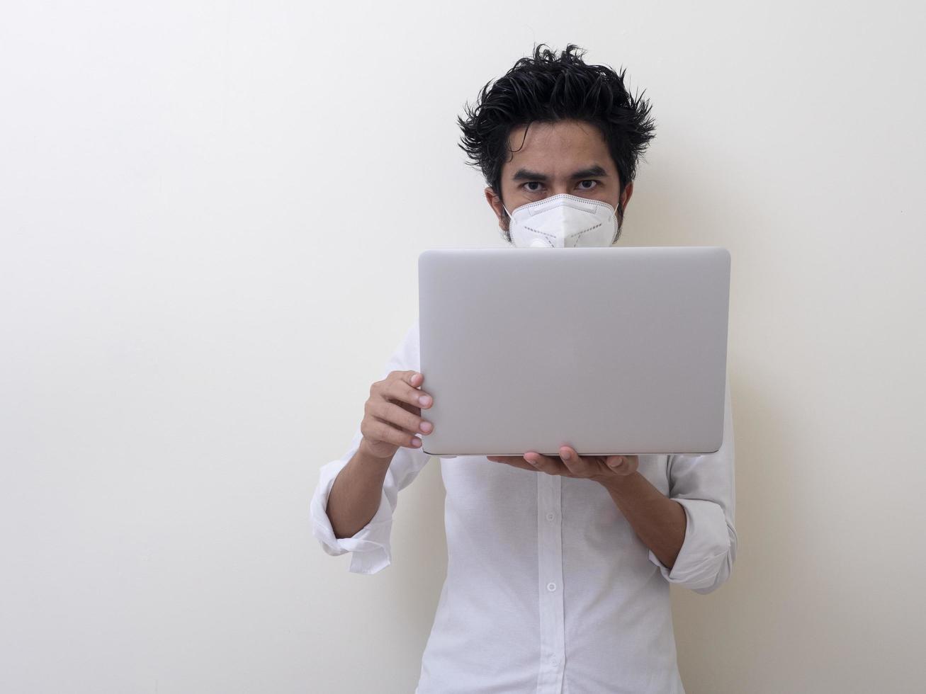 Business man in medical face mask works on laptop at home photo