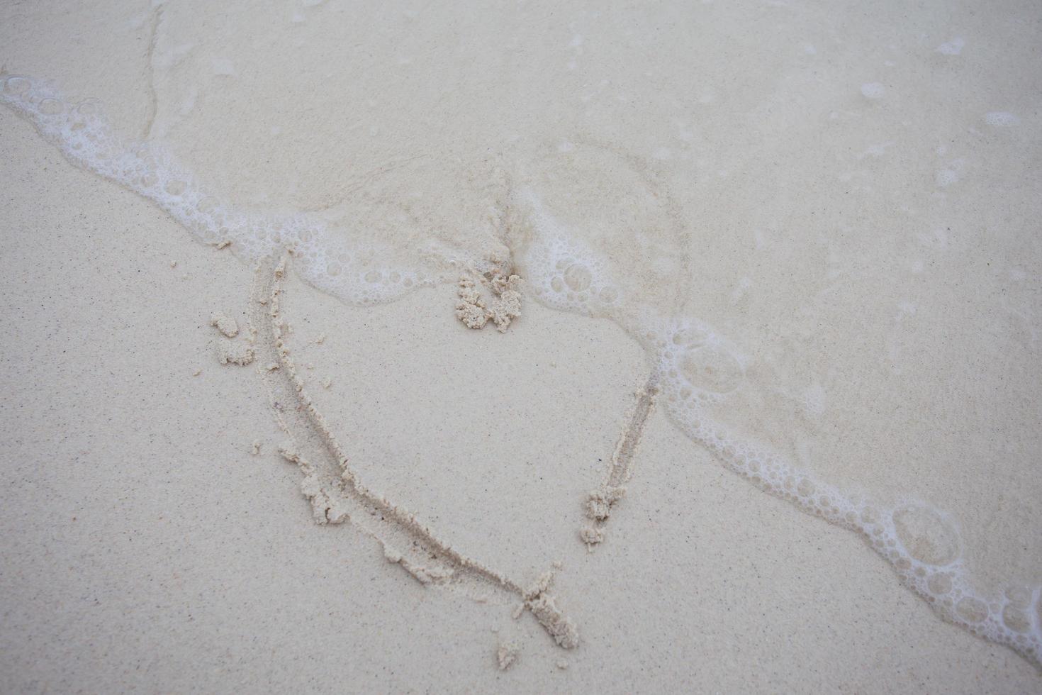 corazones dibujados en la arena de una playa foto