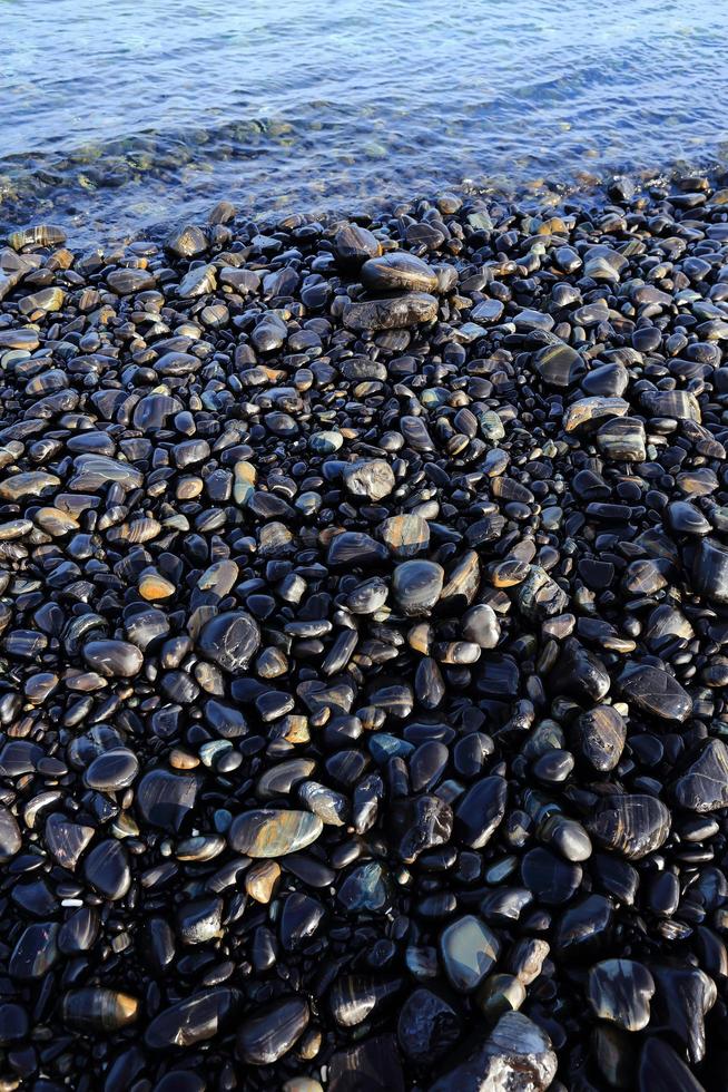 Colorful pebbles touching wave photo