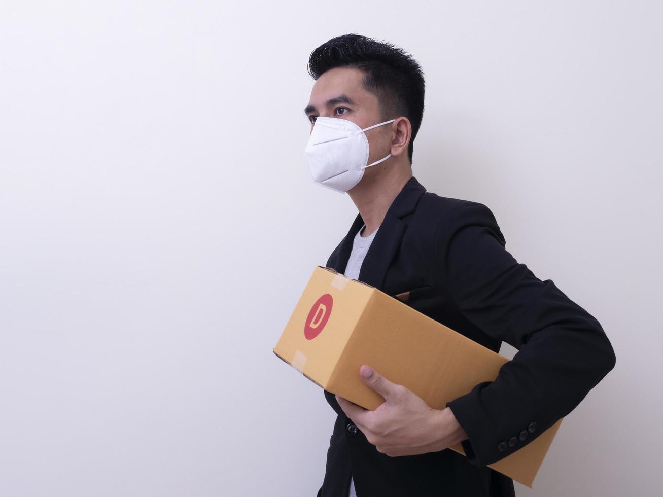 Happy delivery service employee in medical face mask carry cardboard box in hand photo