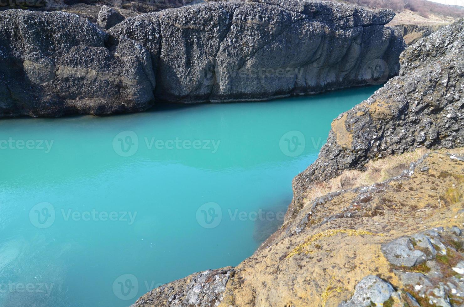 Cloudy aqua water going through a rock formation photo