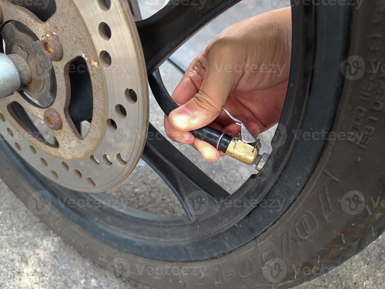 Asian man inflates old motorcycle wheels for road safety photo