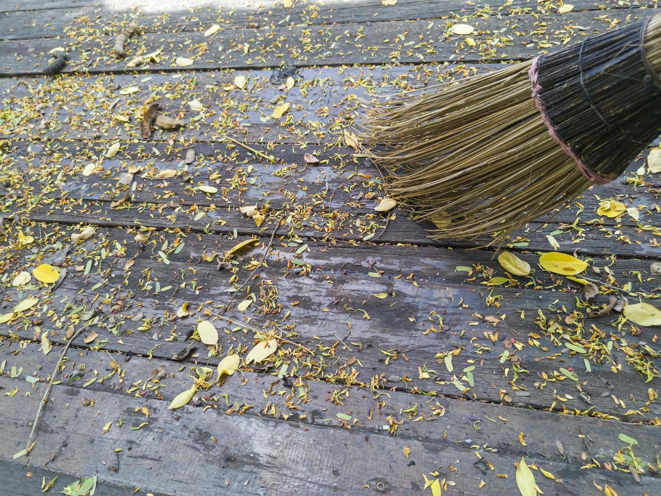 escoba y hojas de otoño en suelo de madera foto