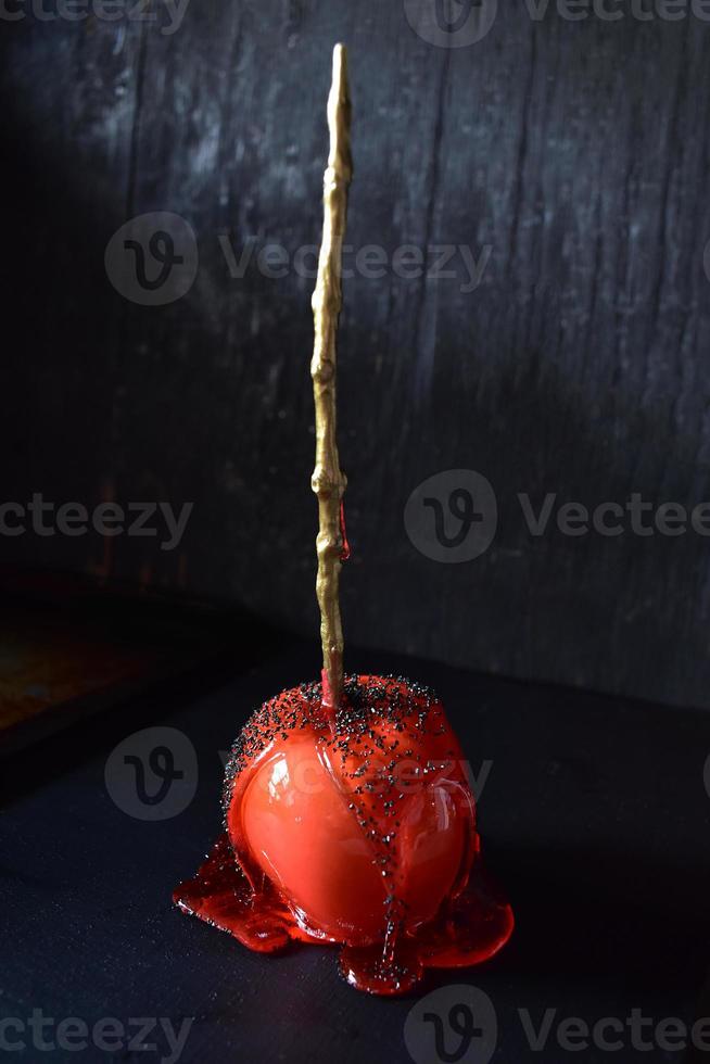 Halloween candy apple with gold stick on dark background photo