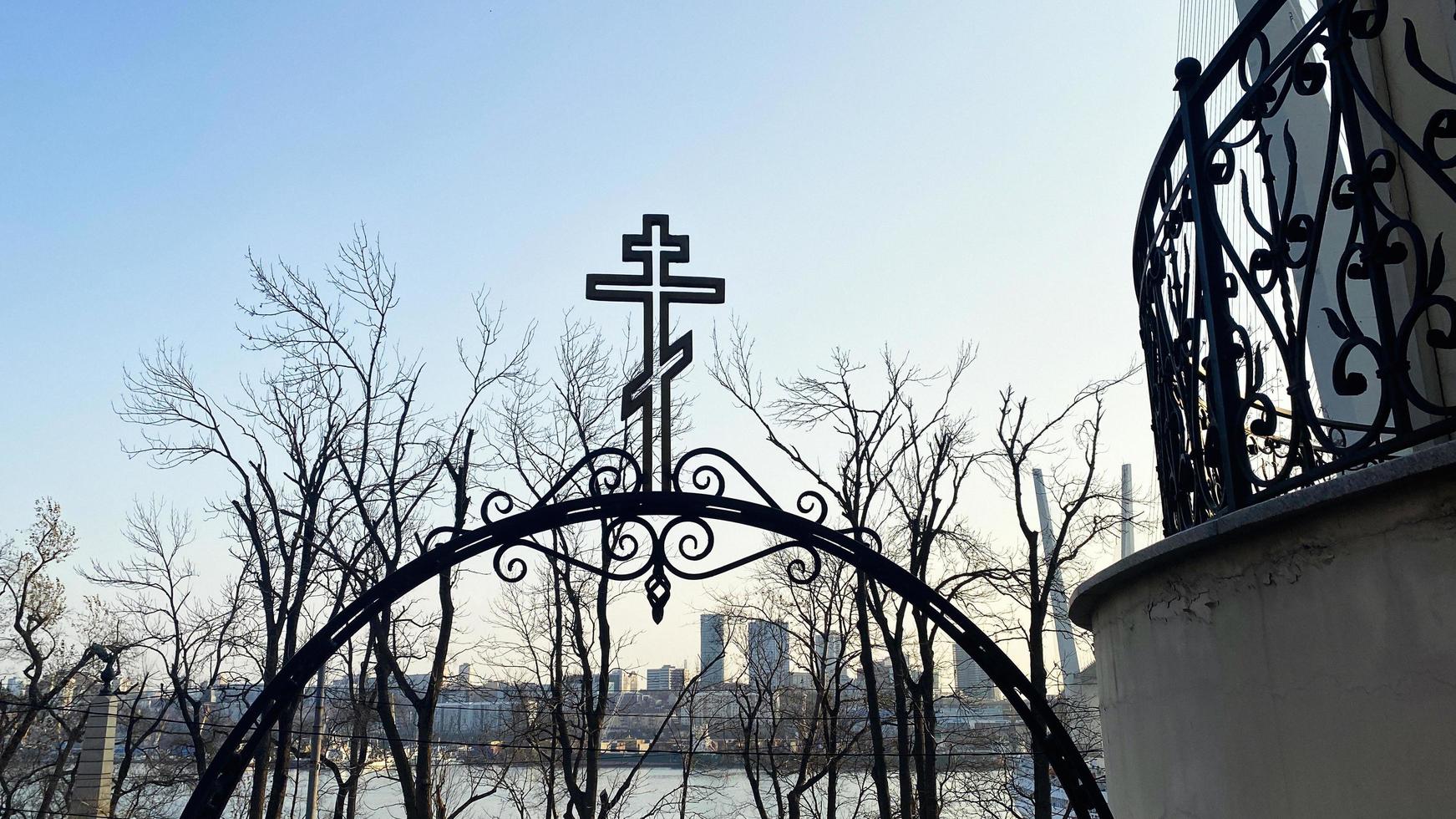 Vladivostok, Russia. Arch with a metal cross on the background of the city photo