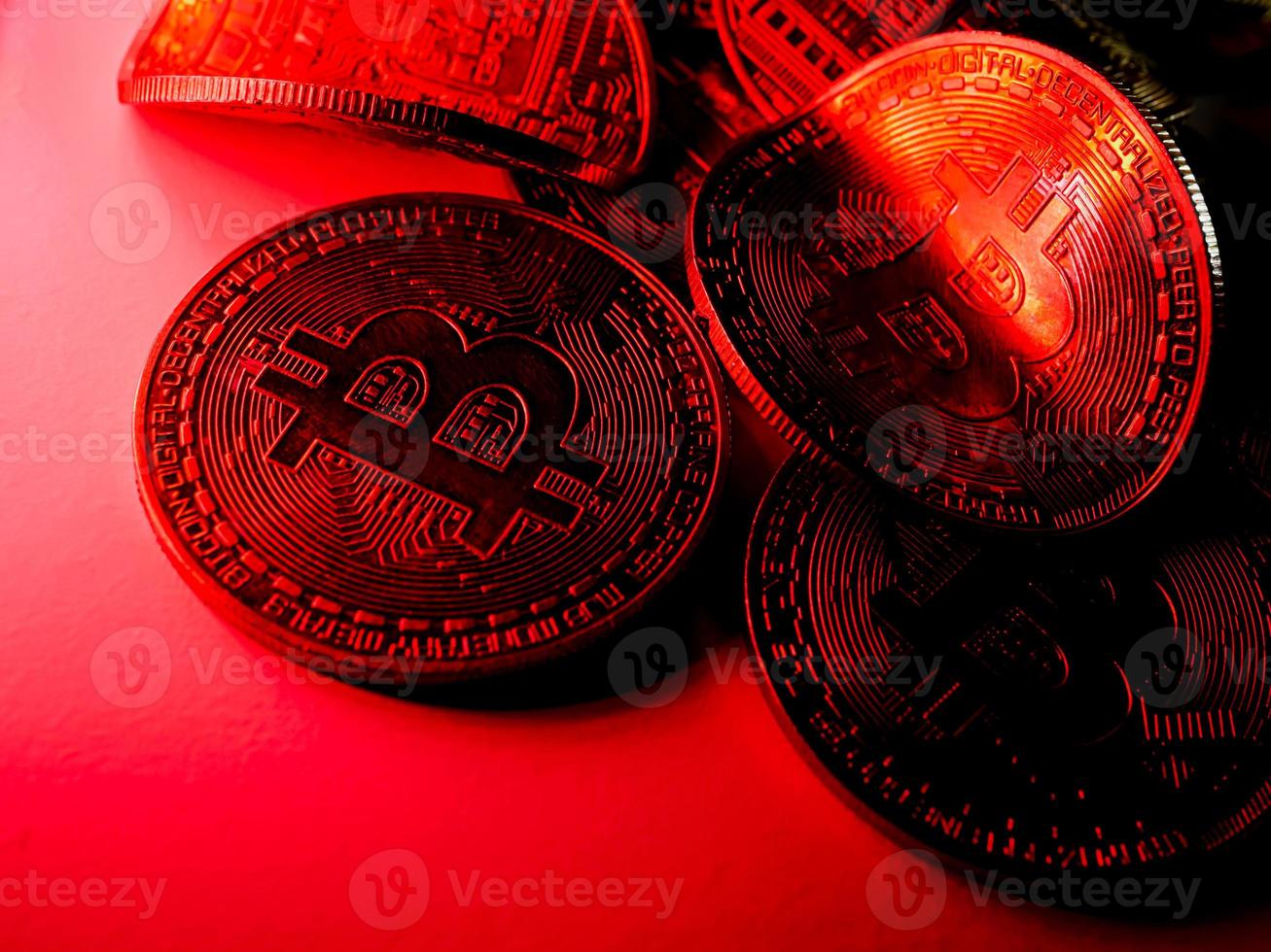 Twisted coins with bitcoin symbol on red light. Concept of a cryptocurrency market crisis. photo