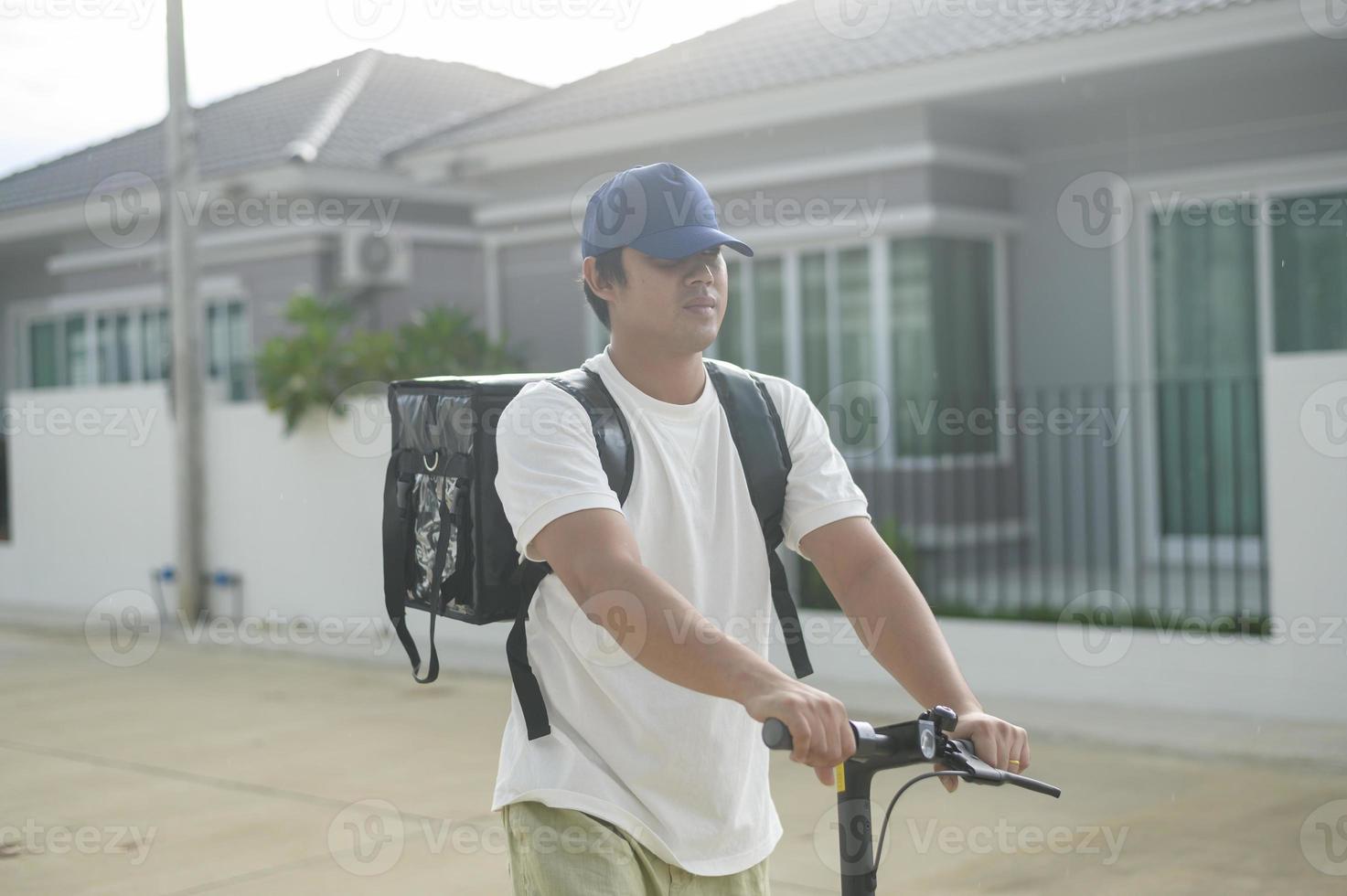 Smiling delivery man with thermal backpack riding on an electric scooter, deliver online concept photo