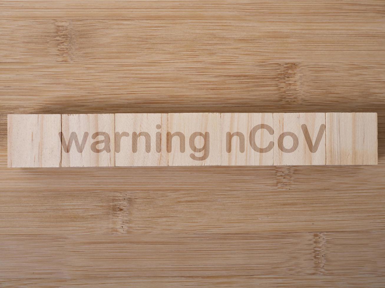warning nCoV word written on wood block. warning nCoV text on wooden table for your desing, coronavirus concept top view photo
