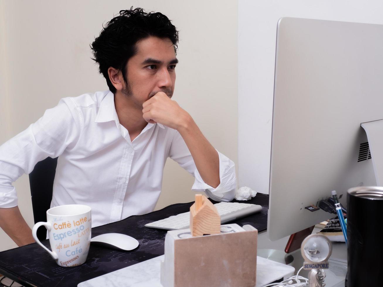 Serious Asian man is working with laptop in his apartment bedroom in concept of Work From Home and Work at Home photo