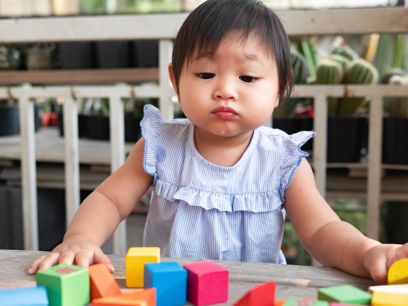Little asian girl playing with wood blocks on the floor photo