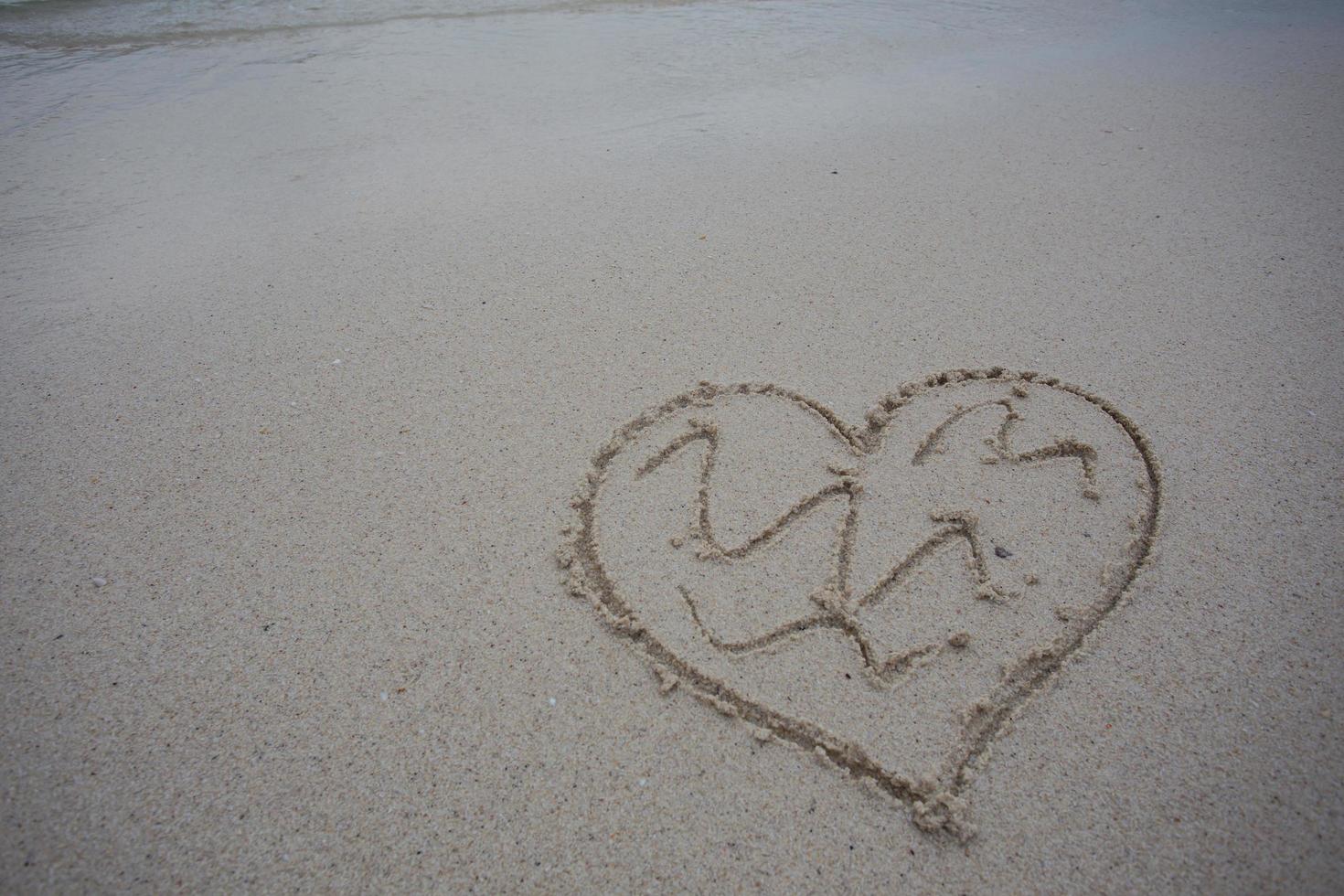 corazones dibujados en la arena de una playa foto