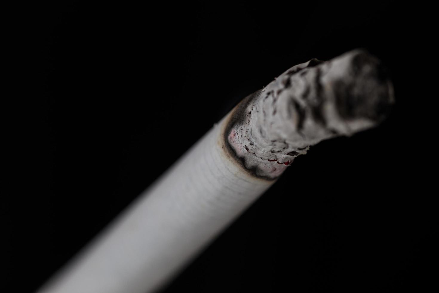 Burning cigarette with smoke on black background photo