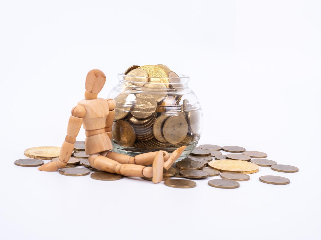 Miniature wooden figure sits on spilled jar with coins. Business concept with coins. photo