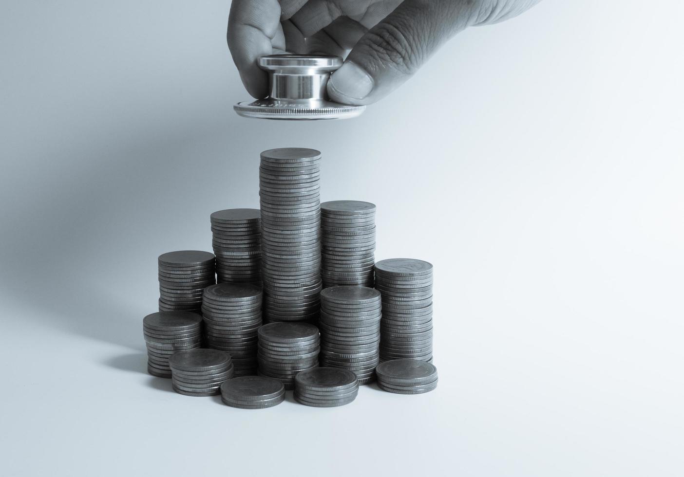 estetoscopio en pila de monedas, sobre fondo blanco. dinero para atención médica, ayuda financiera, concepto foto