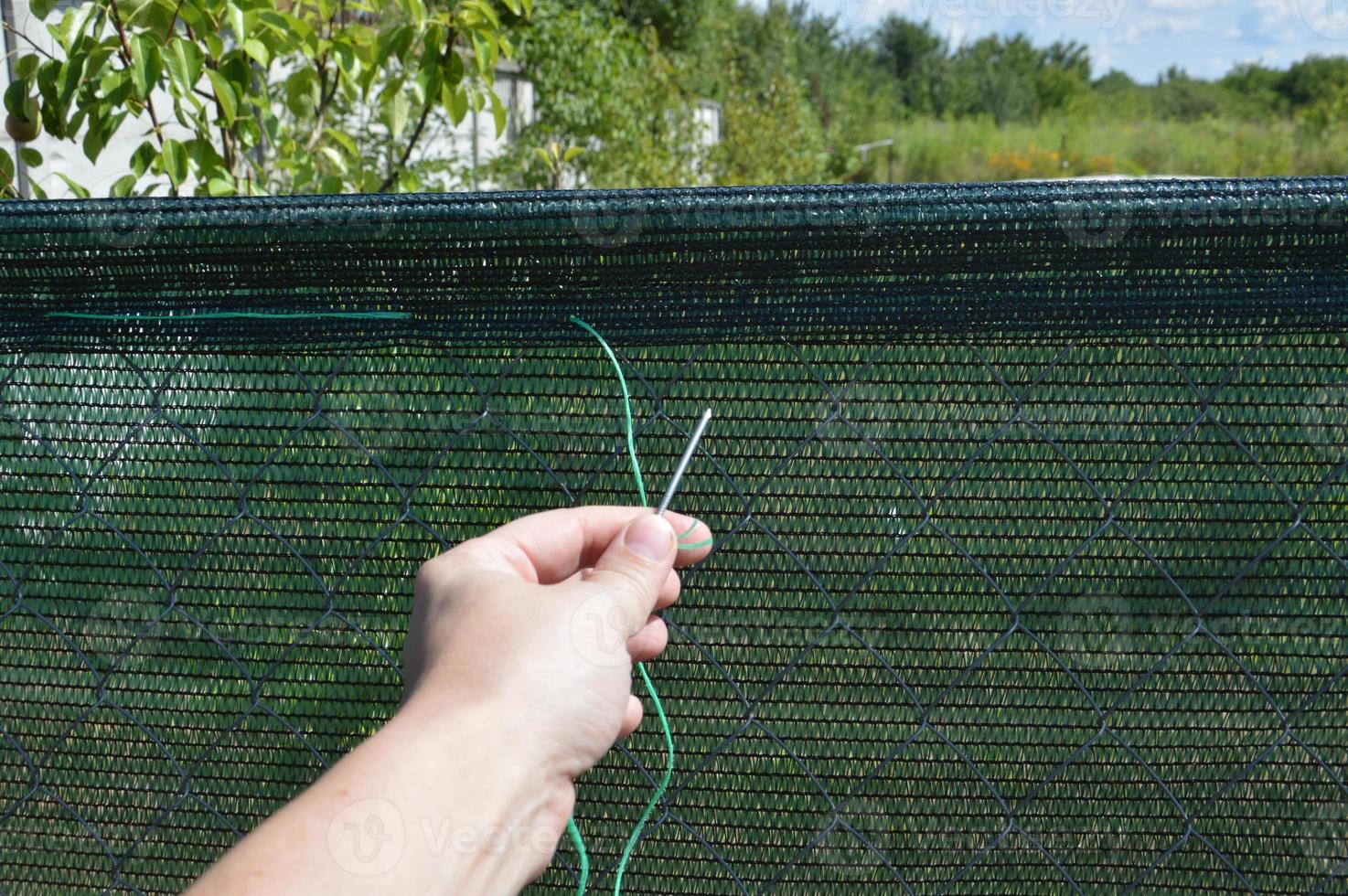 Installation of a shading net on a chain-link fence photo