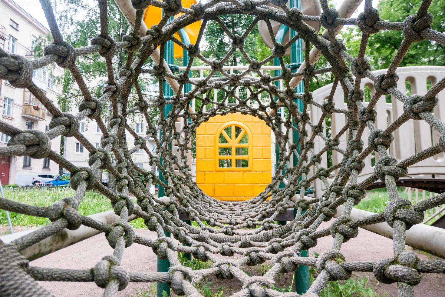 Inside view of a long rope mesh pipe, at the end of the tunnel yellow playground blurred background photo