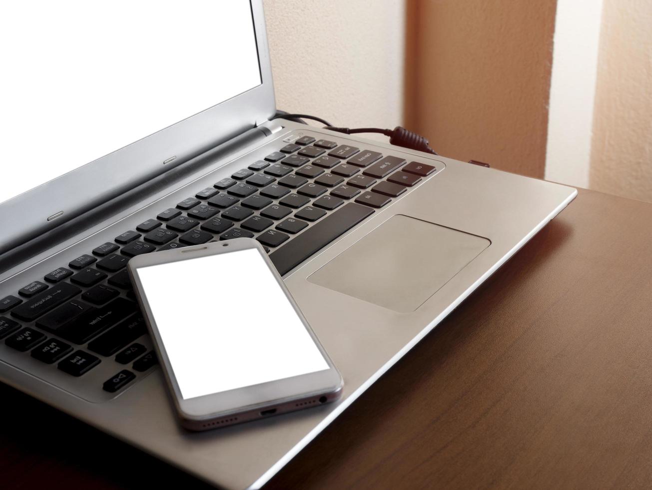 Smartphone white screen mockup on a laptop computer black keyboard white screen mock-up on a desk office with copy space and composition. The concept for using an advertising banner text photo